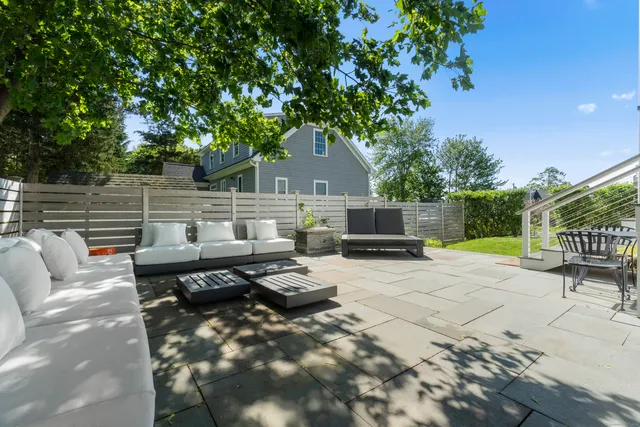 a view of a patio with couches and a table and chairs with wooden fence and plants