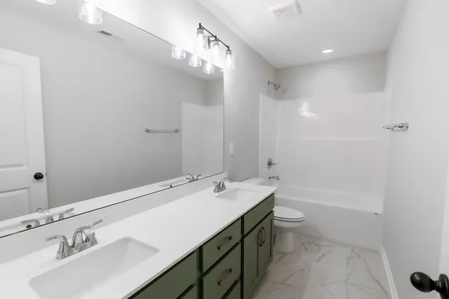 a bathroom with a sink a toilet a mirror and shower