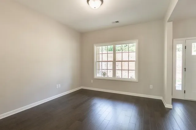 an empty room with wooden floor and windows