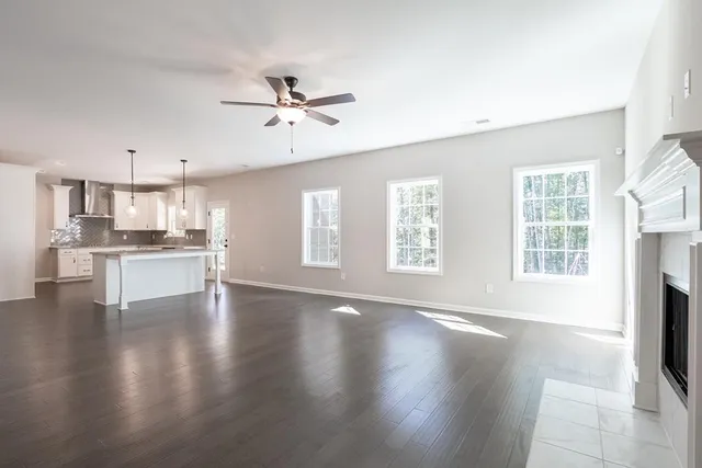 a view of an empty room with wooden floor and a kitchen