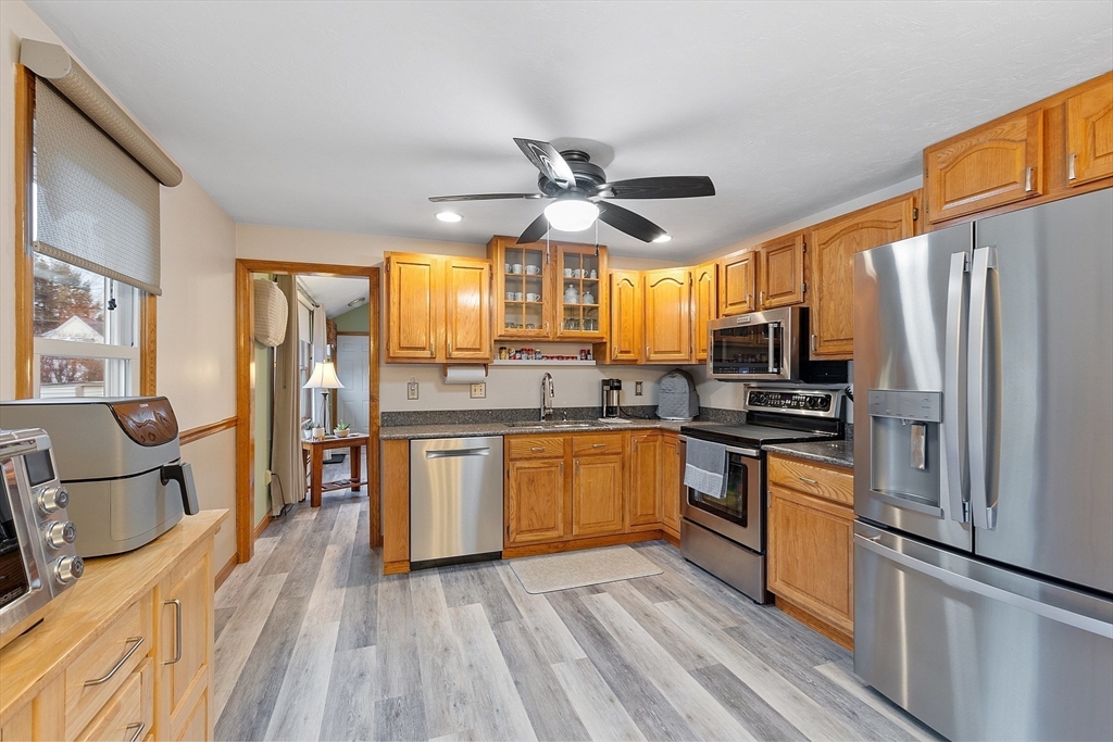 27 Lancaster Road Shirley, MA 01464 - Photo 6 of 41 a kitchen with stainless steel appliances granite countertop a refrigerator a stove top oven a sink dishwasher and wooden cabinets