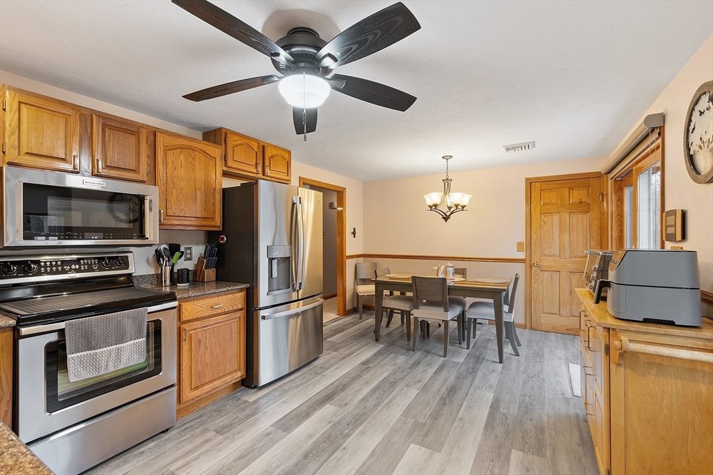 27 Lancaster Road Shirley, MA 01464 - Photo 8 of 41 a kitchen with stainless steel appliances granite countertop a stove top oven a refrigerator a dining table and chairs with wooden floor