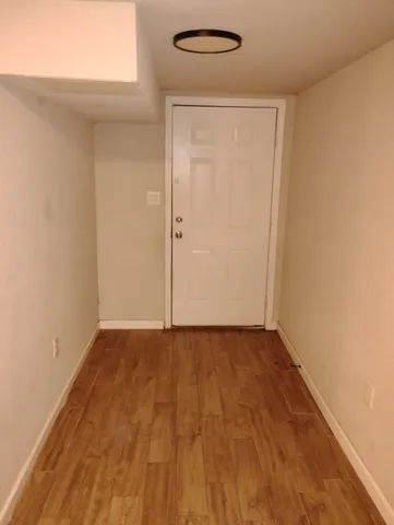 a view of an empty room with wooden floor and a window