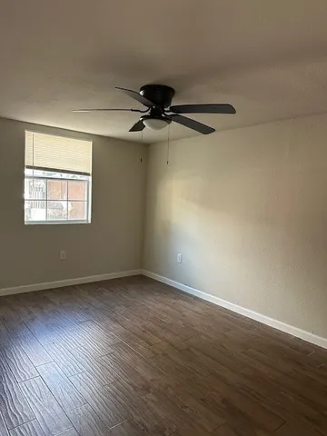 a view of an empty room with a window and wooden floor