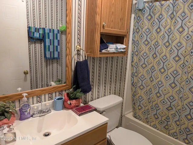 a bathroom with a sink a toilet and shower curtain