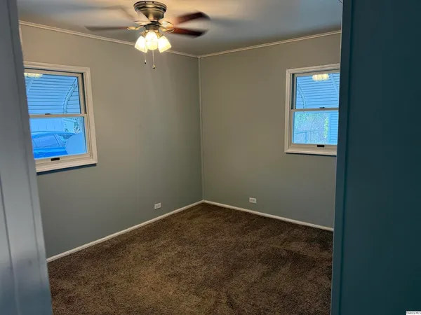 an empty room with windows and fan
