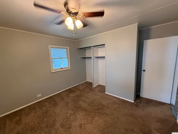 an empty room with closet and a chandelier fan