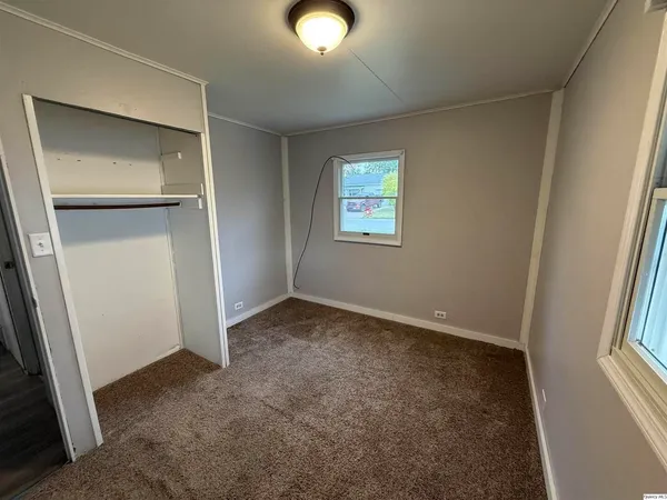 an empty room with windows and closet