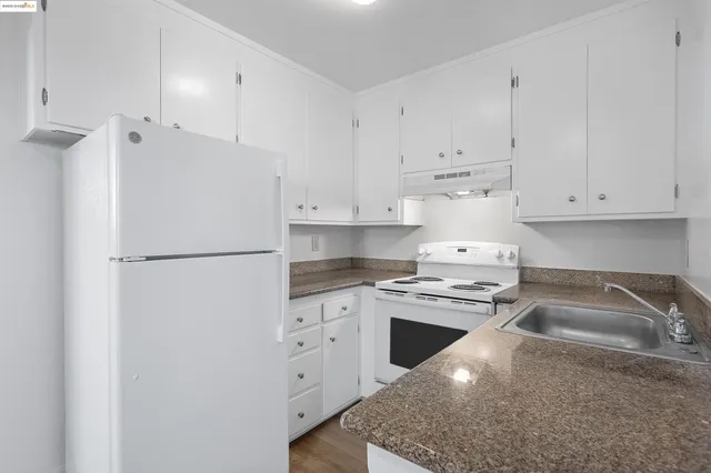 a kitchen with granite countertop a sink stove and refrigerator