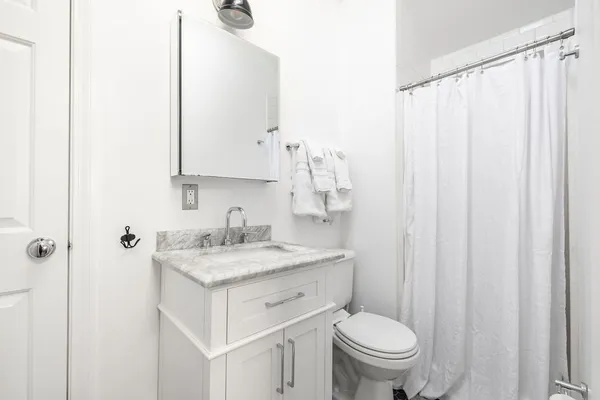 a bathroom with a granite countertop sink toilet and a mirror