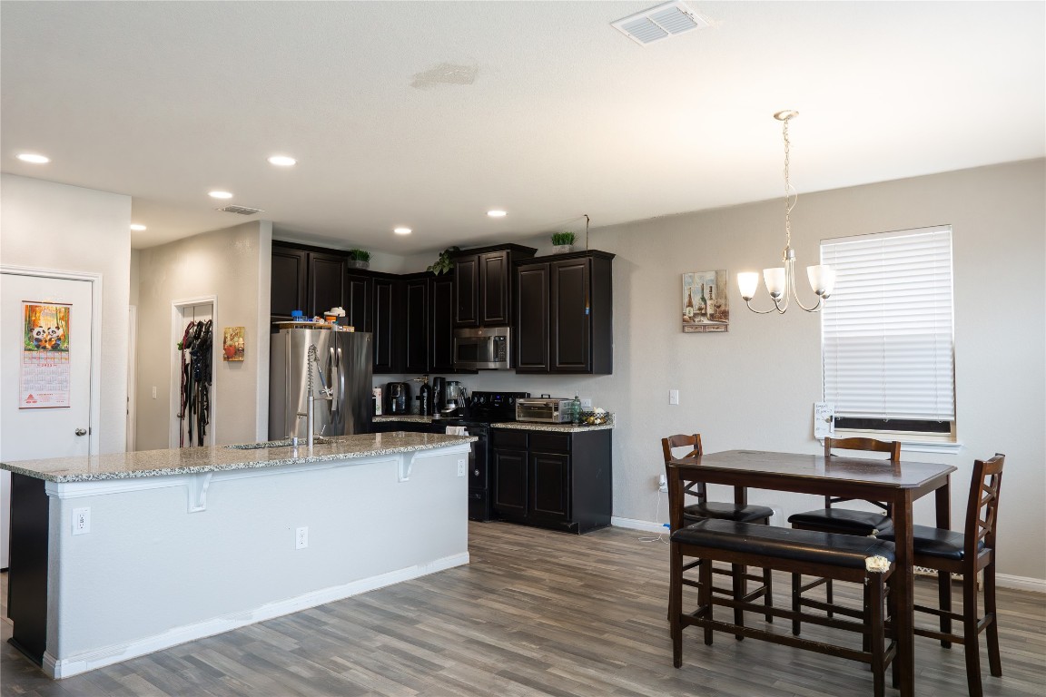 124 Guemal Road Buda, TX 78610 - Photo 3 of 14 a kitchen with stainless steel appliances kitchen island granite countertop a table chairs and a refrigerator