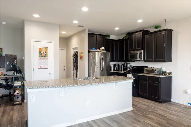 a large kitchen with stainless steel appliances granite countertop a stove a sink a refrigerator and a granite counter tops with wooden floor