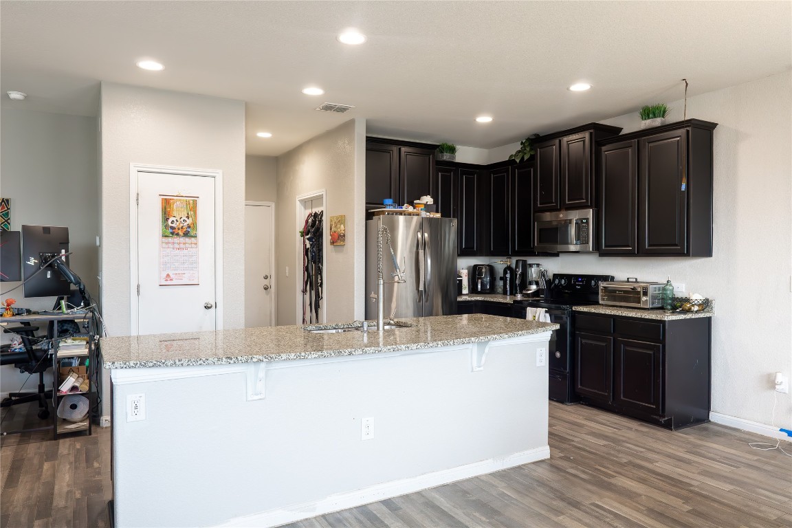 124 Guemal Road Buda, TX 78610 - Photo 4 of 14 a large kitchen with stainless steel appliances granite countertop a stove a sink a refrigerator and a granite counter tops with wooden floor
