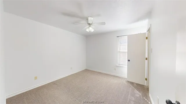 an empty room with a ceiling fan and a window