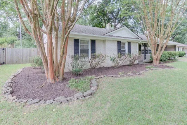 a front view of a house with a garden and yard