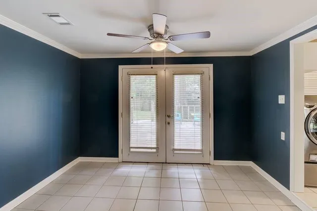 an empty room with wooden floor chandelier fan and windows