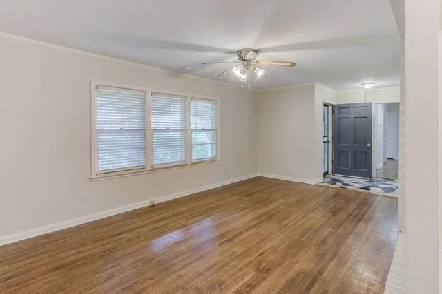 a view of an empty room with a window and wooden floor