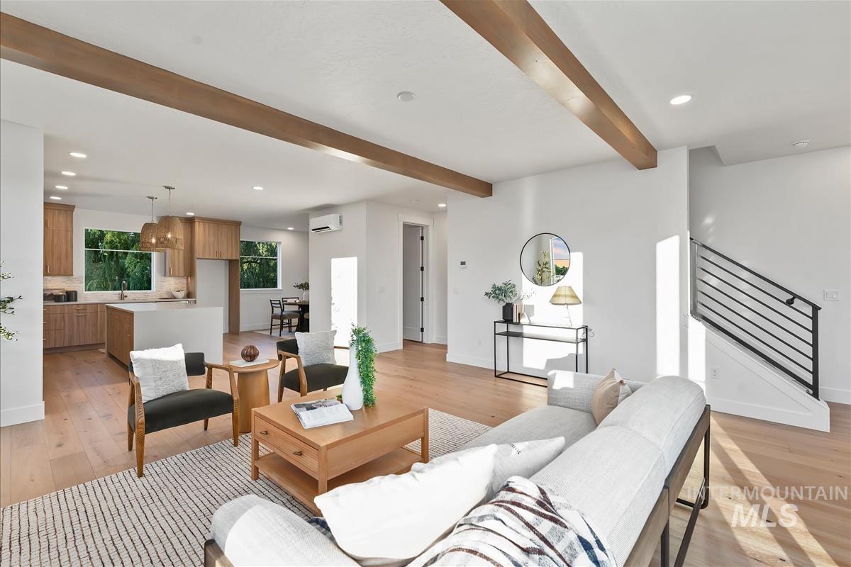 3219 West Moore Street Boise, ID 83702 - Photo 18 of 36 Expansive main living space featuring exposed wood ceiling beams, light wood-finish flooring, and a modern open-tread staircase with horizontal metal railings