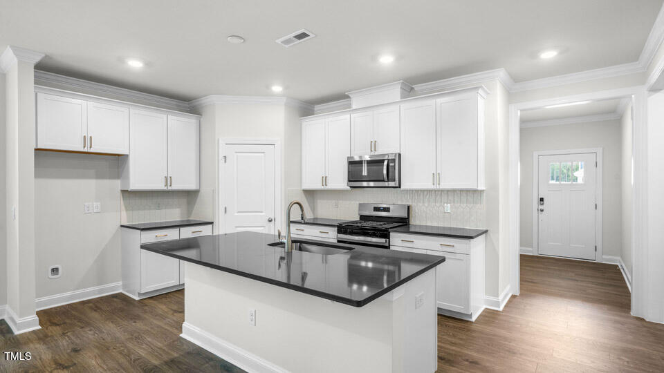 2222 Redpoll Drive Apex, NC 27539 - Photo 7 of 38 a kitchen with stainless steel appliances granite countertop a sink stove and refrigerator
