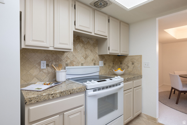 6936 South 775 East, Unit B Midvale, UT 84047 - Photo 10 of 33 Kitchen with white electric range oven, tile counters, backsplash, white cabinetry, and light tile patterned floors