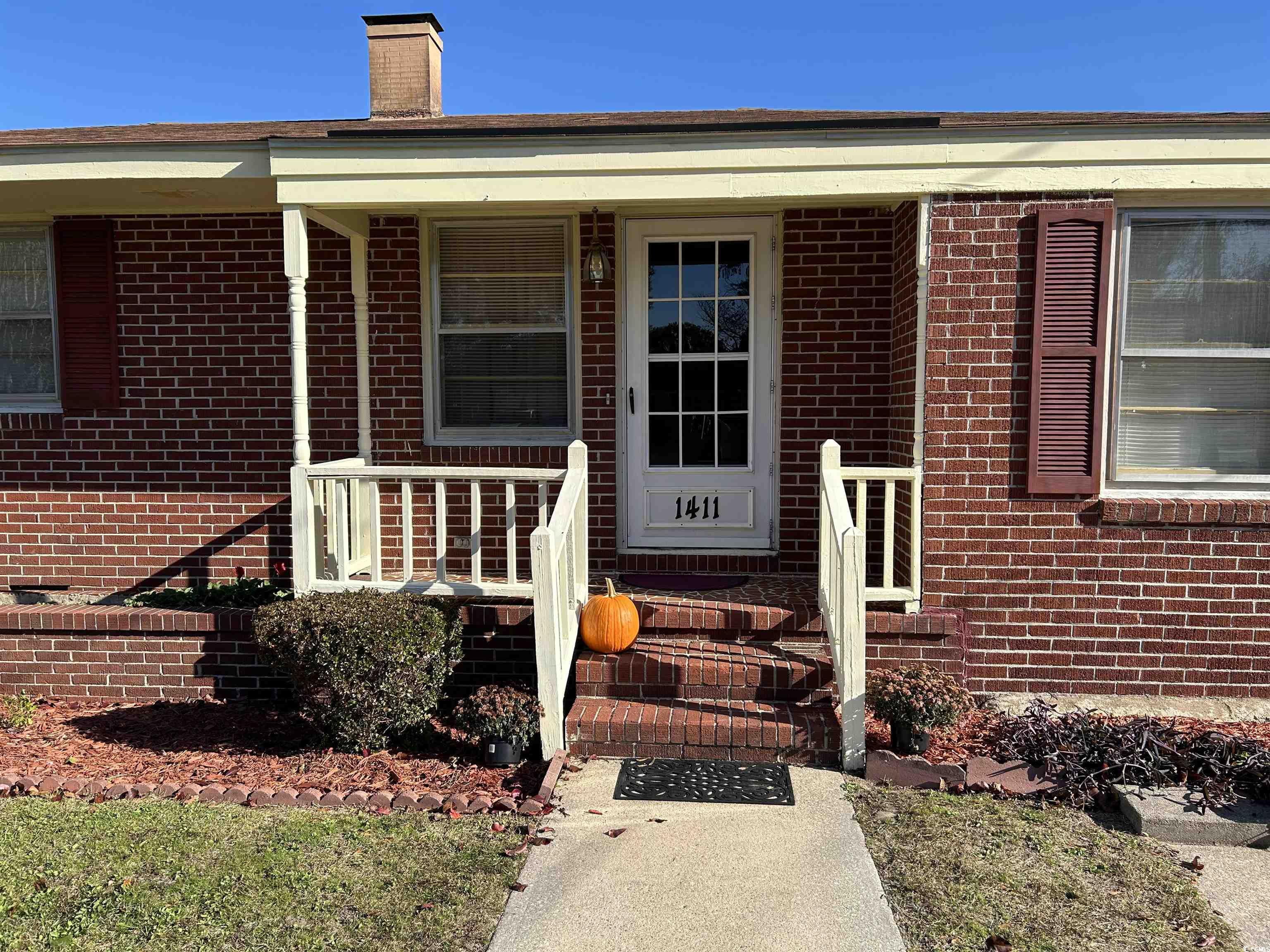1411 East Harrison Street Dillon, SC 29536 - Photo 4 of 40 Entrance to property featuring brick siding, a porch, and a chimney