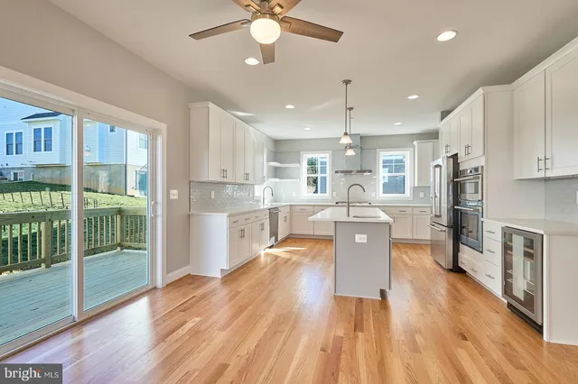 a kitchen with stainless steel appliances granite countertop a refrigerator a oven a sink dishwasher and white cabinets with wooden floor