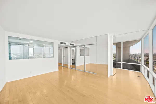 a view of an empty room with wooden floor and windows