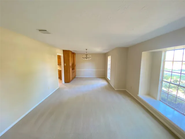 a view of a big room with windows and chandelier fan