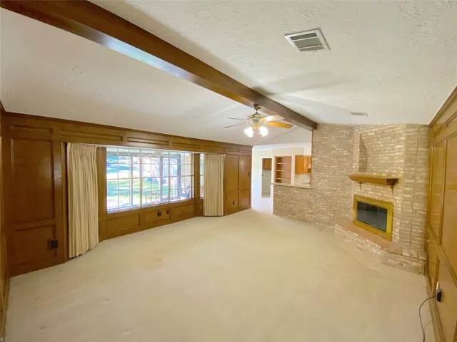 a view of an empty room with a fireplace and a window