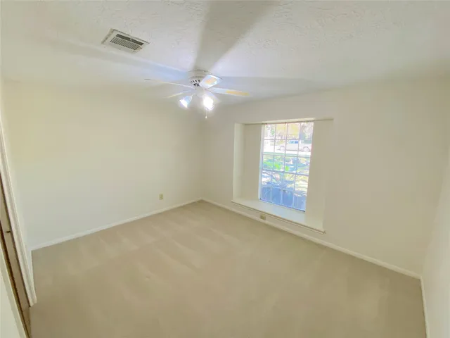 an empty room with a chandelier fan and windows
