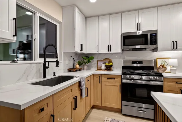 a kitchen with stainless steel appliances granite countertop a sink a stove and cabinets