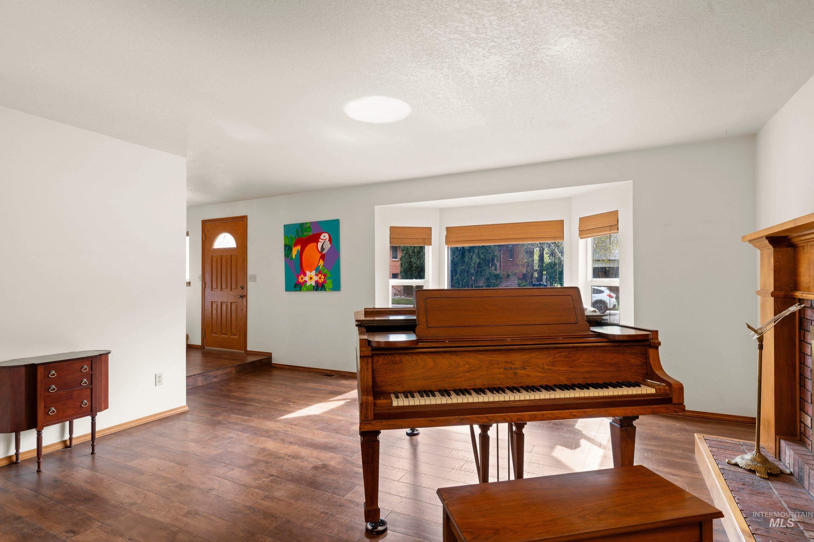 1921 Incline Way Meridian, ID 83646 - Photo 10 of 50 Living area featuring wood-finish flooring, a bay window with natural light, a wood-paneled front entry door, a skylight, and a fireplace with a brick surround and wood mantle