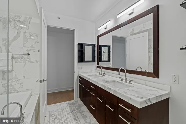 a bathroom with a tub shower sink and mirror