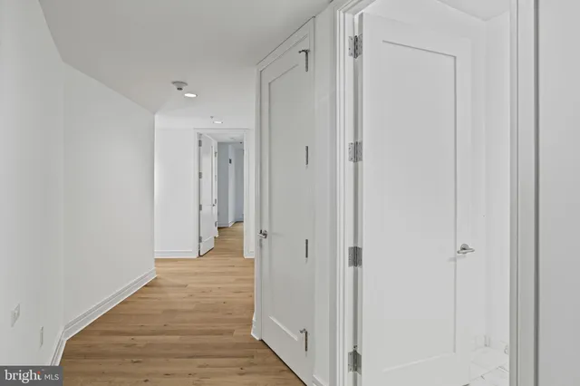 a view of a hallway with wooden floor and a bathroom