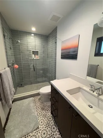 a bathroom with a sink a toilet a mirror and shower
