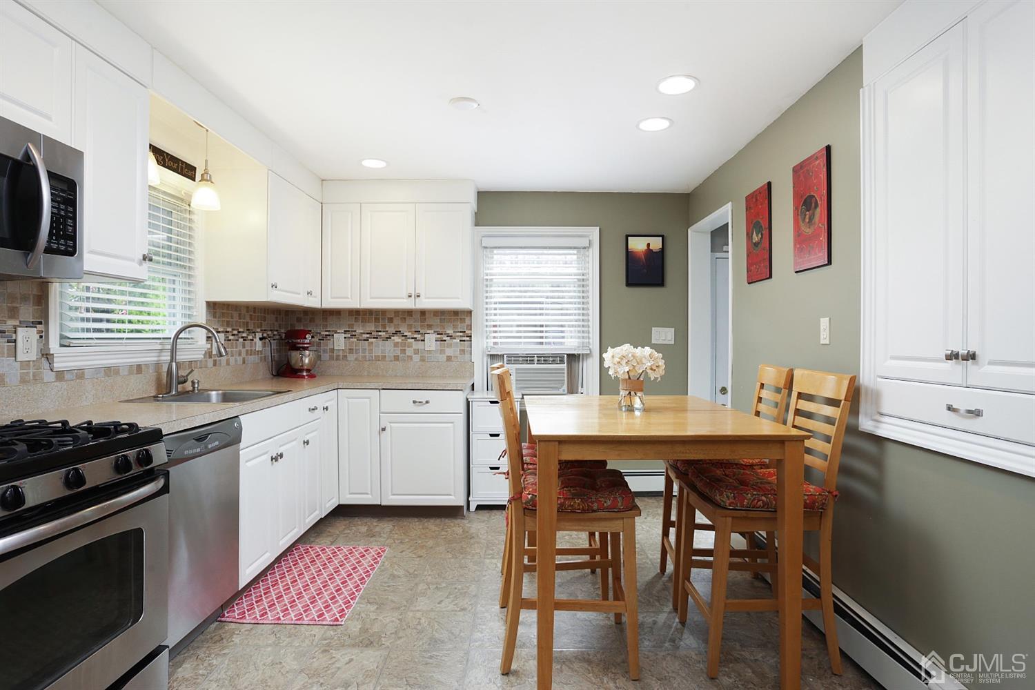 39 West Hill Road Colonia, NJ 07067 - Photo 14 of 26 a kitchen with stainless steel appliances granite countertop a stove a sink dishwasher a microwave oven and a dining table with wooden floor