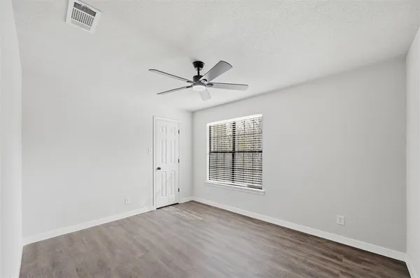 an empty room with wooden floor and ceiling fan