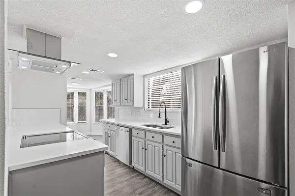 a kitchen with stainless steel appliances granite countertop a refrigerator a sink and white cabinets