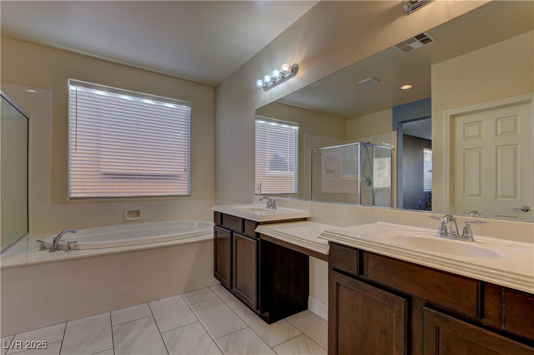 972 Rue Grand Paradis Lane Henderson, NV 89011 - Photo 16 of 32 Bathroom with two vanities, a shower stall, a garden tub, and light tile patterned floors
