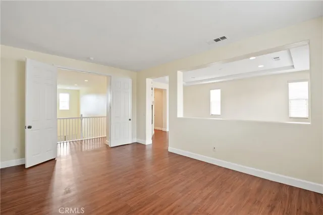 a view of an empty room with window and wooden floor