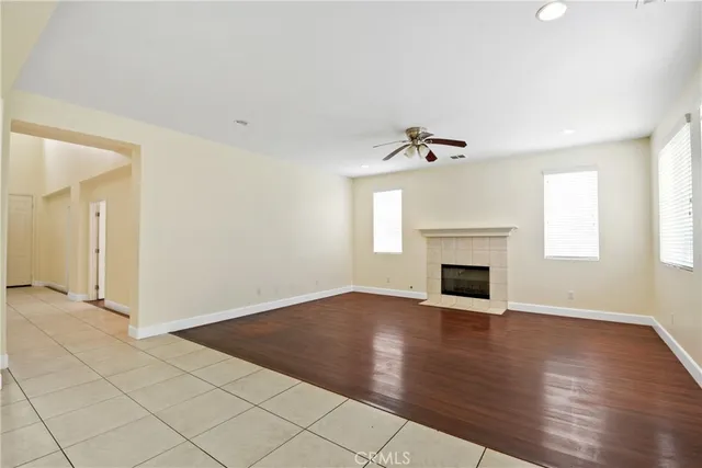 an empty room with wooden floor fireplace and windows