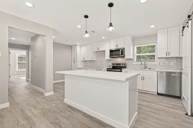 a kitchen with cabinets stainless steel appliances a sink and a window