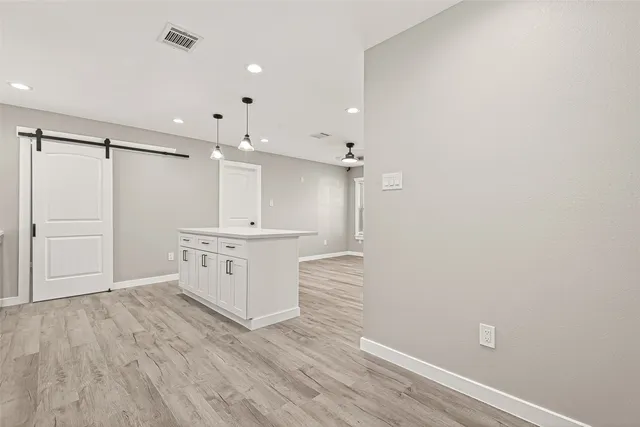 a hall with kitchen island white cabinets and wooden floor
