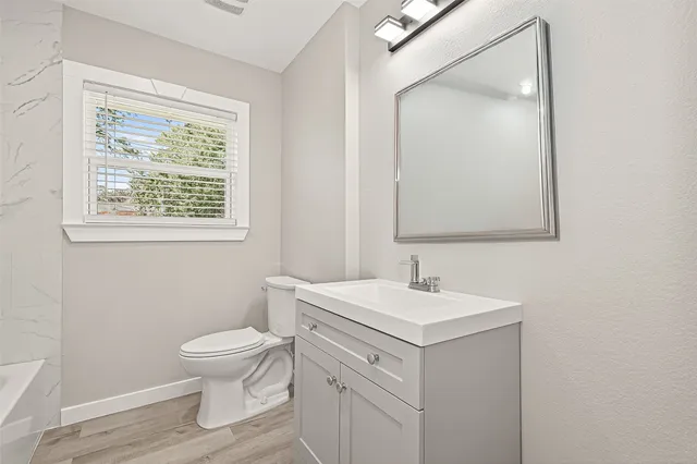 a bathroom with a toilet sink vanity and mirror