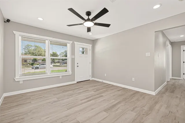 an empty room with wooden floor and windows
