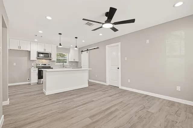 a view of kitchen with cabinets wooden floor and stainless steel appliances