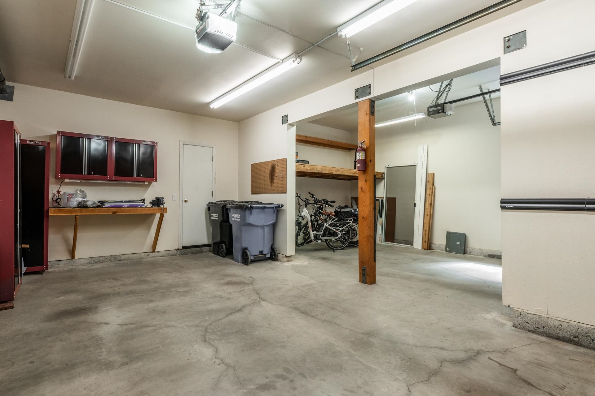 272 Ridge Way Mammoth Lakes, CA 93546 - Photo 44 of 55 Garage interior featuring a concrete floor, overhead fluorescent lighting, and two automatic garage door openers