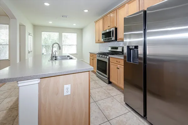 a kitchen with stainless steel appliances granite countertop a refrigerator a stove and a sink