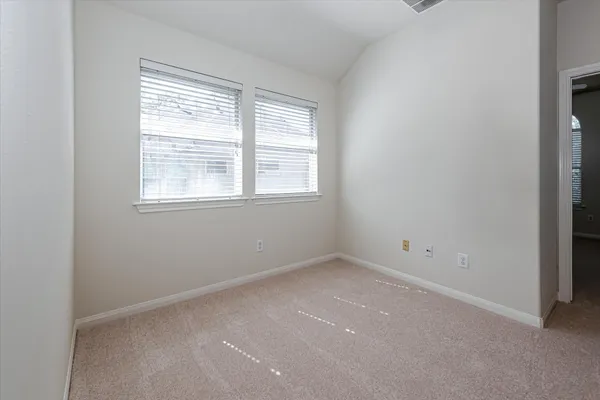 an empty room with windows and chandelier fan