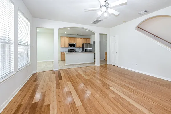 a view of empty room with wooden floor and fan